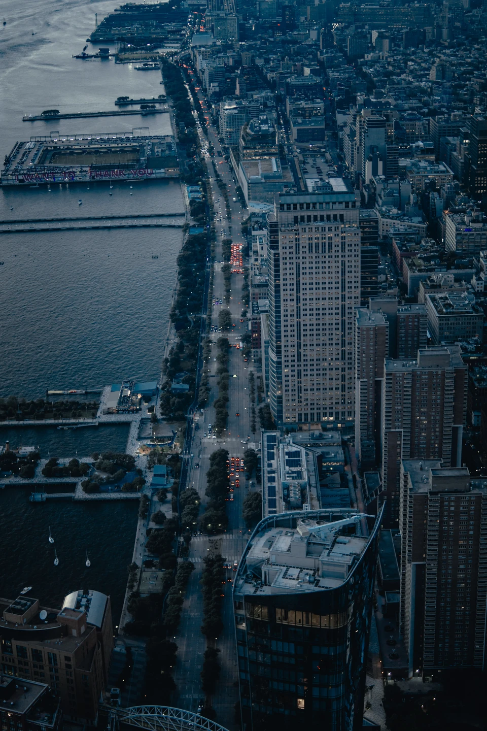 View straight down Manhattan's west side at dusk, with piers along the Hudson River