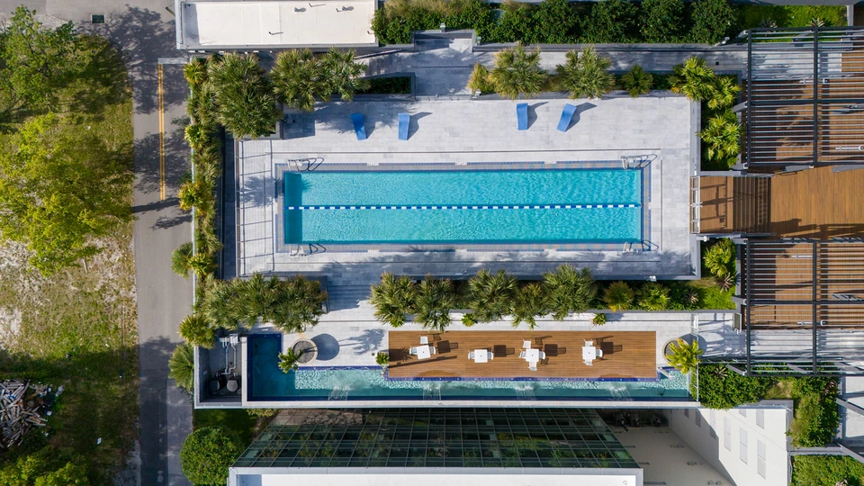 Top-down aerial view of a rooftop lap pool surrounded by greenery