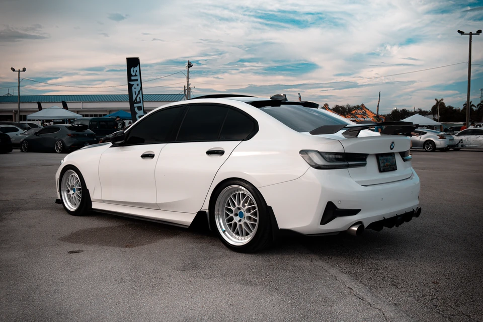 White BMW sedan with silver wheels at an outdoor car meet
